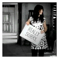 a woman is holding a sign that says `` really sorry '' in her hands .