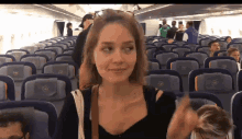a woman sitting on a plane with a seat that says l on it