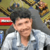 a man is sitting in a chair and smiling in front of a clash of clans game .