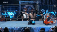 a wrestler is kneeling down in a wrestling ring while another wrestler is being pinned down