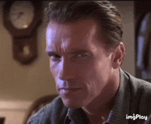 a close up of arnold schwarzenegger 's face with a clock in the background .