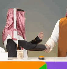 a man in a keffiyeh is shaking hands with another man in a suit .