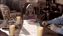 a little girl is sitting at a table with a plate of food