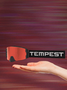 a person is holding a pair of tempest goggles in their hand