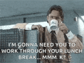 a man in a suit and tie is drinking a cup of coffee while leaning on a cubicle .