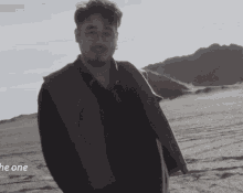 a black and white photo of a man standing in the desert with the words " he one " below him