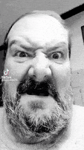 a man with a beard is making a funny face .