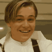 a close up of a man wearing suspenders and a white shirt smiling