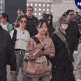 a group of people are walking down a street wearing face masks .