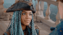 a woman with blue braids is wearing a pirate hat and looking at a man .