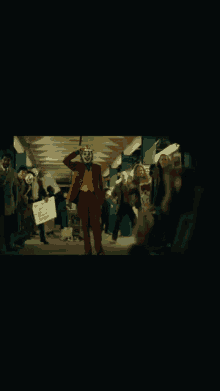 a group of people wearing masks and joker costumes are walking down a subway .