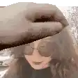 a woman wearing sunglasses and a hat is being touched by a person .