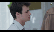 a man in a white shirt and tie looks at a woman in a brown coat