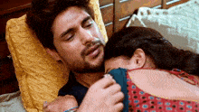 a man and woman are laying on a bed and the woman is holding the man 's head