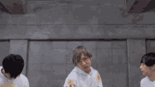 three young men are standing next to each other in front of a wall .