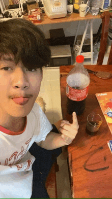 a man sitting at a table with a bottle of coca cola