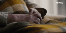 a person laying under a plaid blanket with netflix written on the bottom
