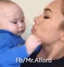 a woman is holding a baby in her arms and kissing it .
