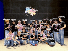 a group of young men are posing for a picture with their names written on the wall behind them