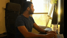 a man sits at a desk typing on a computer keyboard