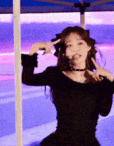 a woman in a black dress is making a peace sign with her hands .