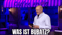 a bald man is standing in front of a coffee shop holding a clipboard and asking what is bubatz ?