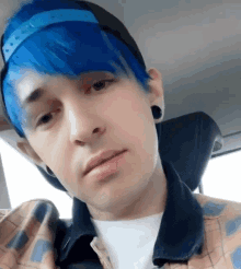 a man with blue hair is wearing a plaid shirt and a baseball cap