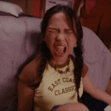 a girl wearing a yellow east coast classic shirt is screaming