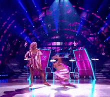 a woman and a man are dancing on a stage with purple lights