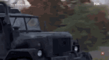 a military vehicle is driving down a street next to a house in a scene from the walking dead .