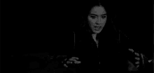 a black and white photo of a woman in a jacket dancing in the dark .