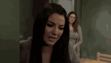 two women are sitting next to each other and one of them is wearing glasses .
