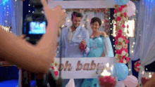 a man and woman are standing in front of a sign that says " oh baby "
