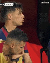 two men are sitting next to each other and one has his hand on his chin