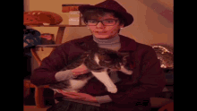 a man in a hat is holding a cat