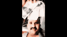 a man with a mustache is holding a picture of a man on his head .