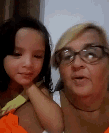 a woman and a little girl are posing for a picture . the little girl is wearing glasses .