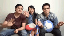 three people are sitting on a couch and one of them has a thumbs up pillow