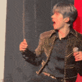 a man singing into a microphone while wearing a black shirt and black jacket