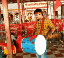 a man playing a drum in front of a building with a sign that says ' shree rani mandir '