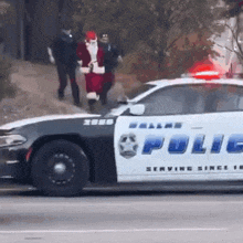 a dallas police car is driving down the street with santa claus on the back