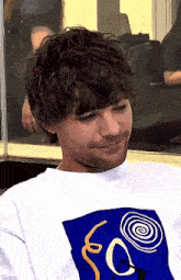 a close up of a man wearing a white t-shirt with a blue graphic on it .