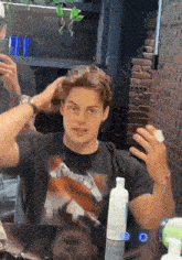 a man wearing a metallica shirt is getting his hair done