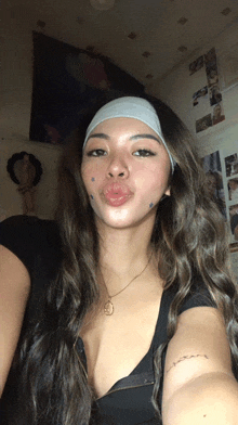 a woman wearing a headband takes a selfie in front of a wall with pictures on it