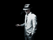 a man in a suit and hat smoking a cigarette