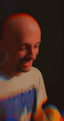 a bald man wearing a t-shirt that says ' hippie ' on it is smiling