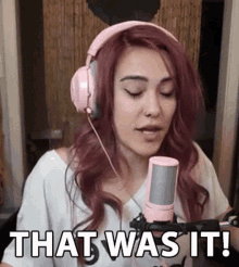 a woman wearing pink headphones is singing into a pink microphone and saying `` that was it '' .