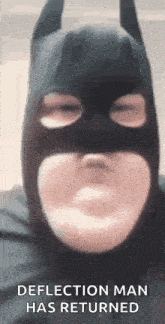 a man is wearing a batman mask and making a face .