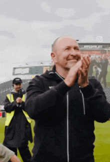 a man is clapping his hands on a field