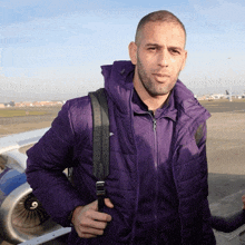 a man in a purple jacket is carrying a black bag